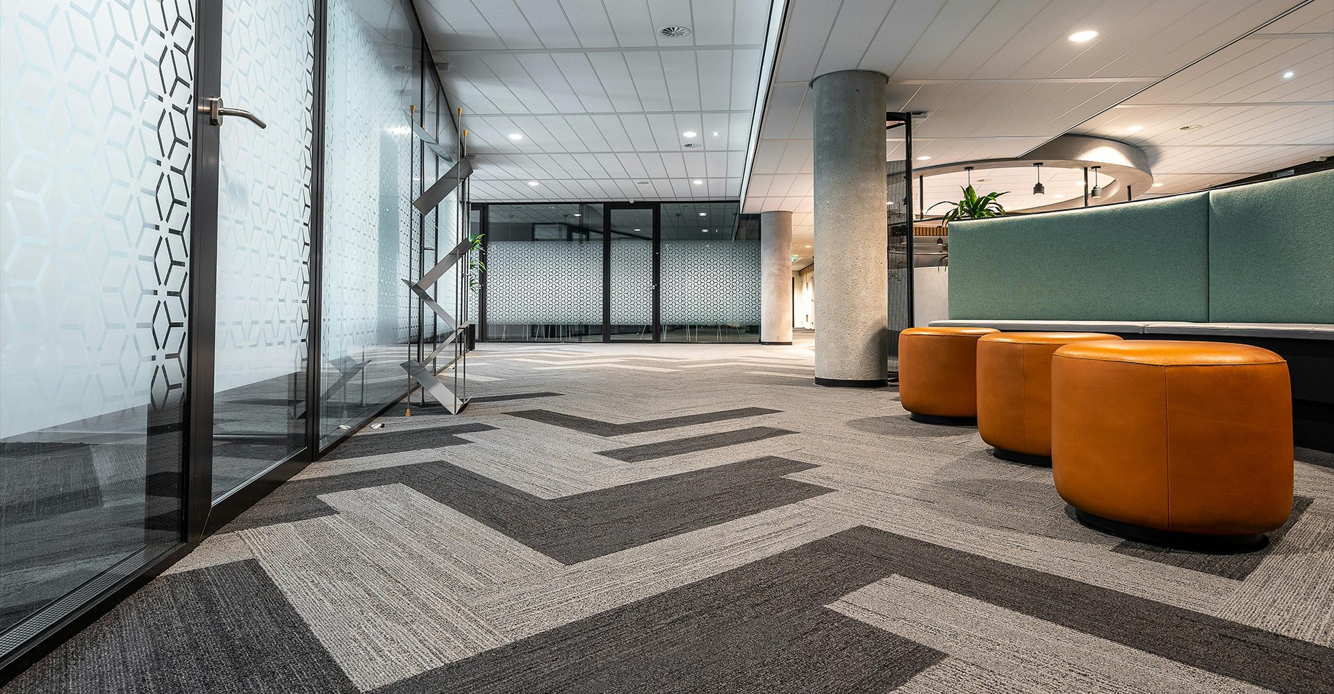 A lobby with an orange couch and glass walls.